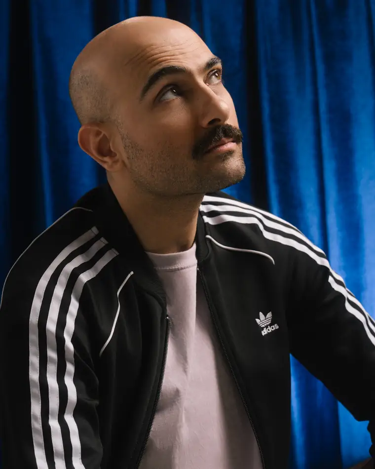 Portrait of Ahmet Kıran against a blue velvet curtain.