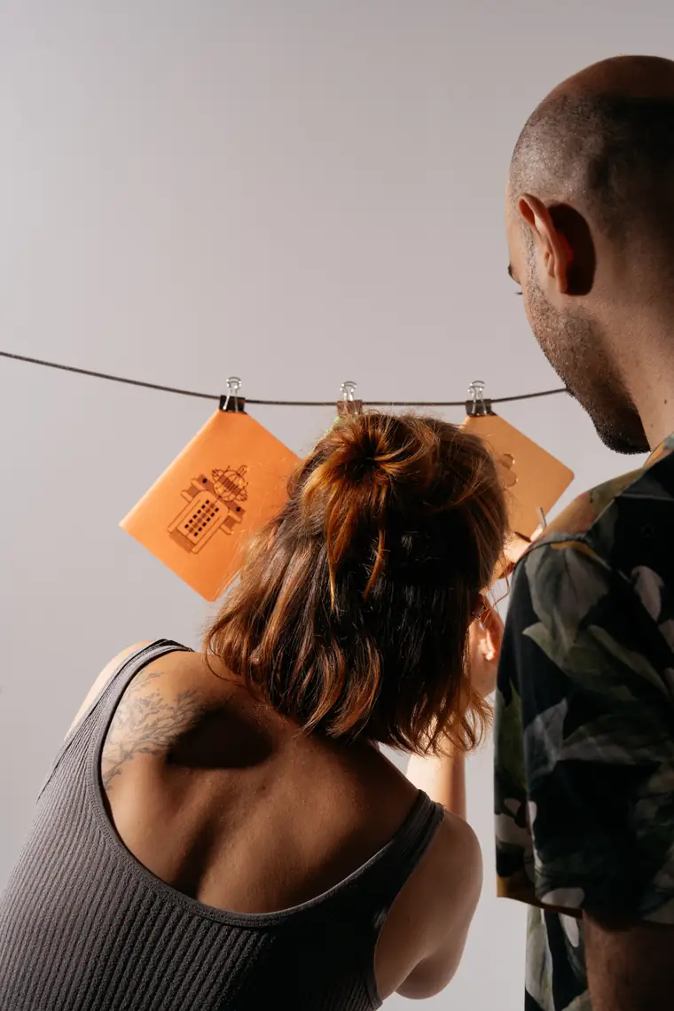 Two of the team adjusting notebooks clipped to a wire.