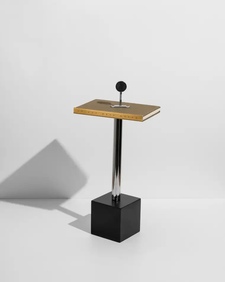 A brass-edged notebook on a black plinth.