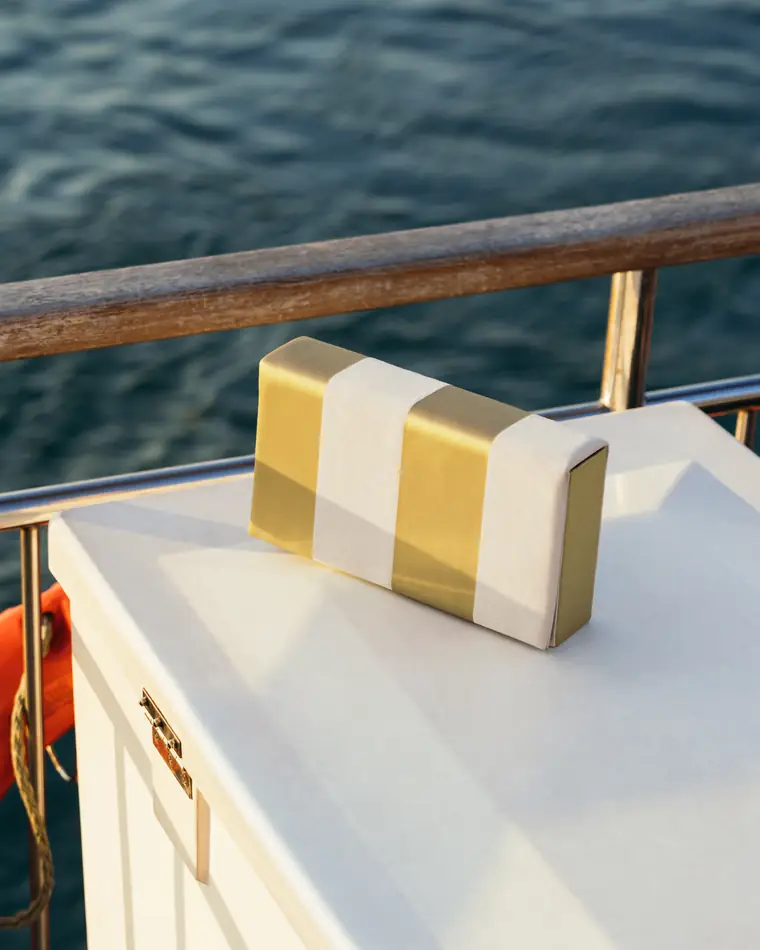 Striped clutch balanced on an ornate bronze door handle.