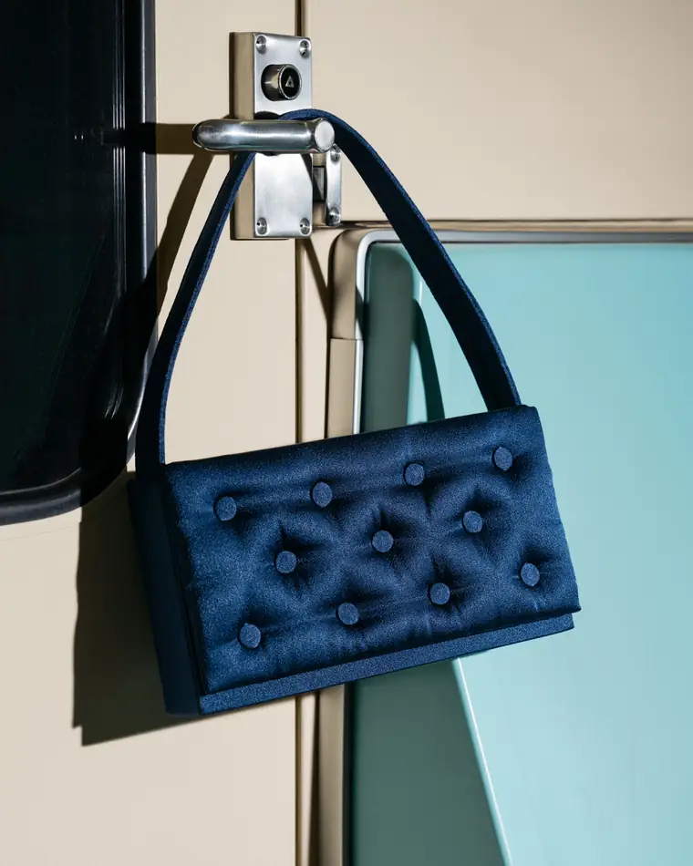 Navy bag hanging from a door handle in a pale interior.