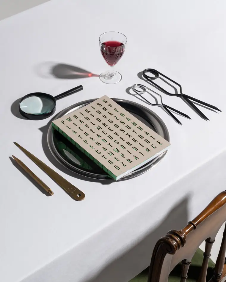 A green word-search notebook served on a metal plate.